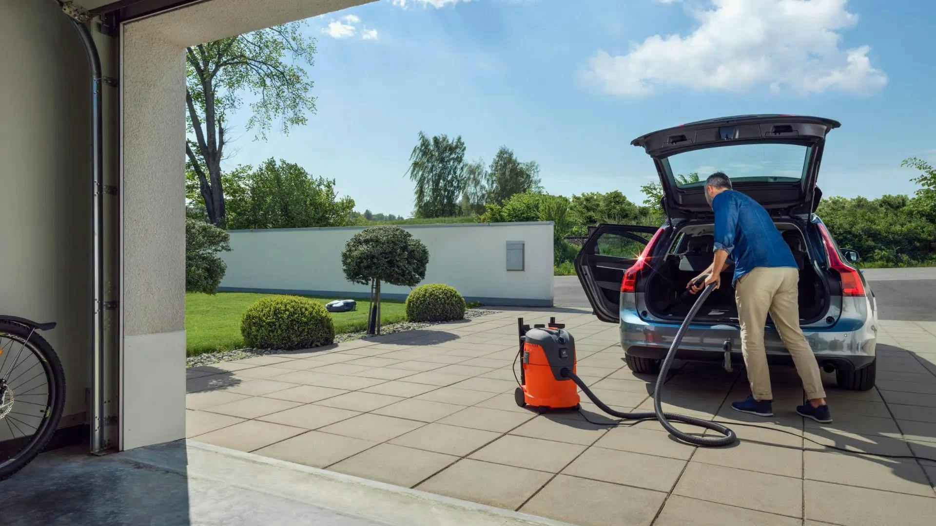 man cleaning boot of car with wet vaccum